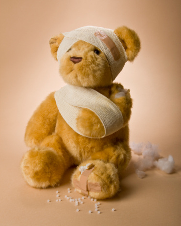 Teddy bear wrapped in bandages with stuffing falling out